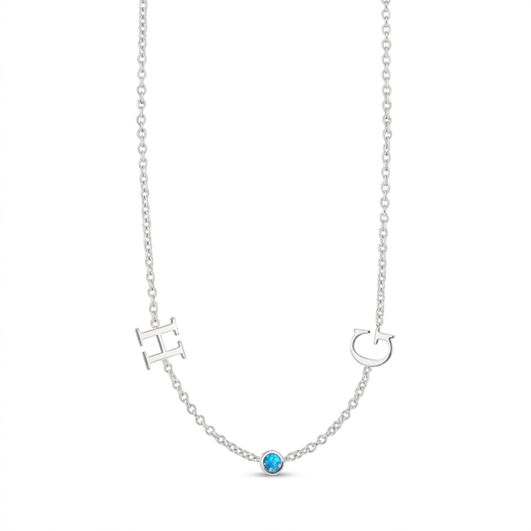 A delicate silver necklace featuring a small oval blue gemstone at the center of a V-shaped chain, with an openwork letter H on one side and a letter C on the other, shown on a plain white background.